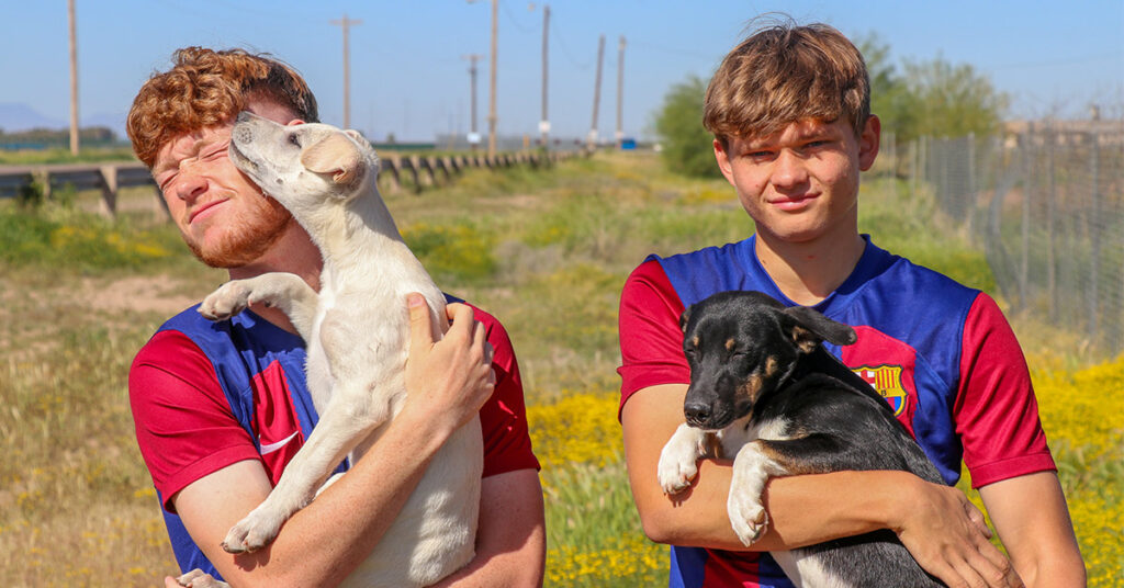 Barca Residency Academy players Connor Bradford and Joel Torbic playing with dogs from Pinal County Animal Care and Control